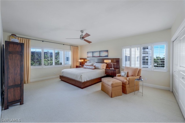 bedroom with light carpet, multiple windows, ceiling fan, and a closet