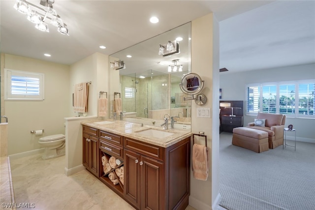 bathroom with toilet, vanity, a wealth of natural light, and a shower with door