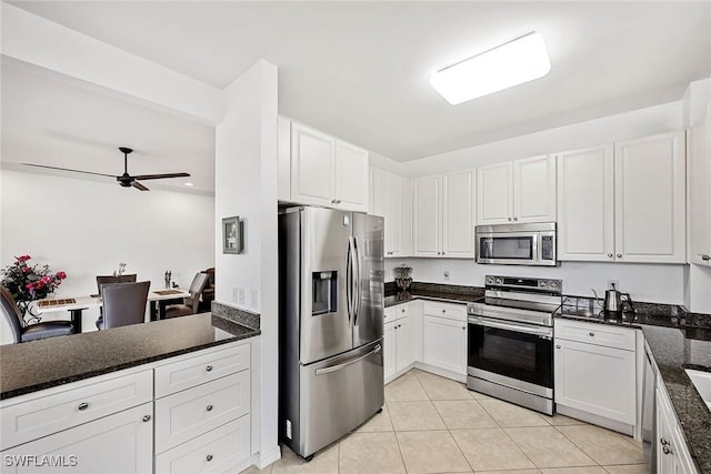 kitchen featuring dark stone counters, ceiling fan, light tile patterned floors, white cabinetry, and stainless steel appliances