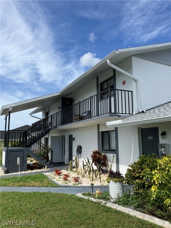 rear view of house featuring a balcony and a lawn