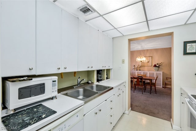 kitchen with white cabinetry, a paneled ceiling, a chandelier, stainless steel range oven, and sink