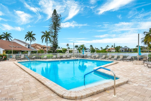 view of pool featuring a water view and a patio