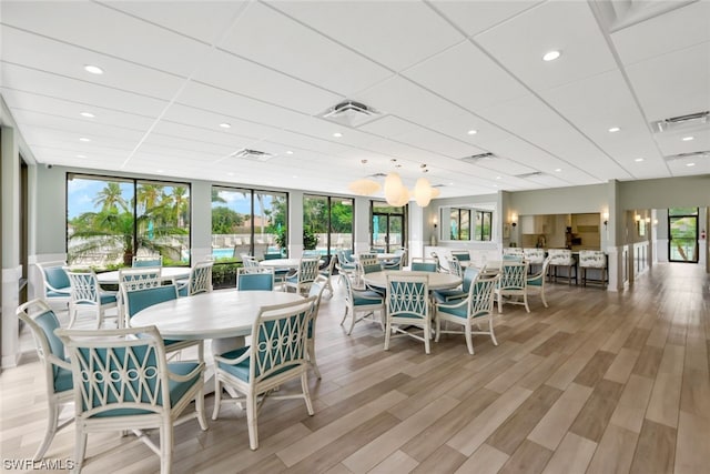 dining room with light hardwood / wood-style flooring and a paneled ceiling