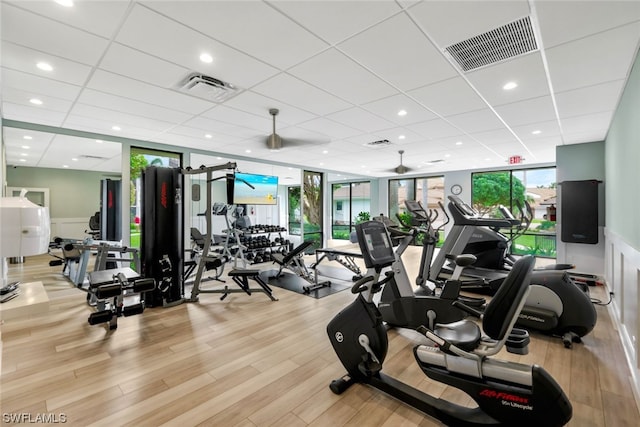 exercise room featuring light hardwood / wood-style floors, a wall of windows, a paneled ceiling, and ceiling fan