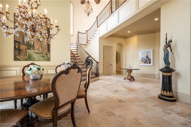 dining area featuring light tile floors, ornamental molding, a chandelier, and a towering ceiling