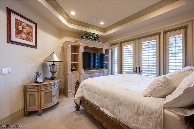 carpeted bedroom with french doors, ornamental molding, and a tray ceiling