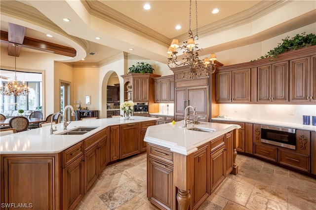 kitchen featuring a notable chandelier, hanging light fixtures, sink, and an island with sink