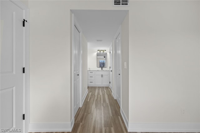 corridor featuring light hardwood / wood-style flooring and sink