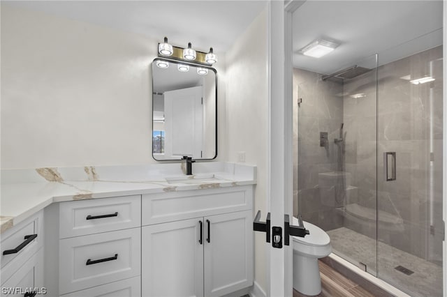 bathroom with toilet, vanity, and a shower with shower door