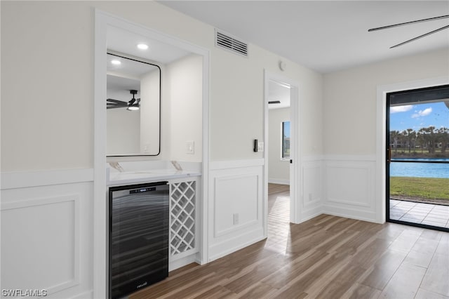 unfurnished living room with wine cooler, wood-type flooring, and ceiling fan