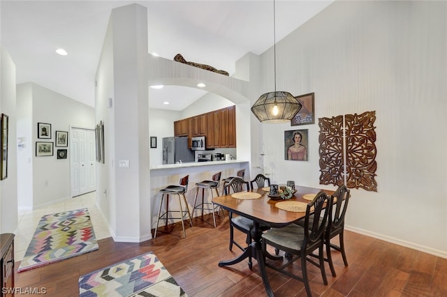 dining space with high vaulted ceiling and dark hardwood / wood-style flooring