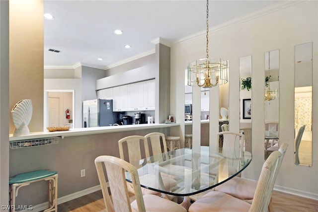 dining room featuring light wood-type flooring, ornamental molding, and an inviting chandelier