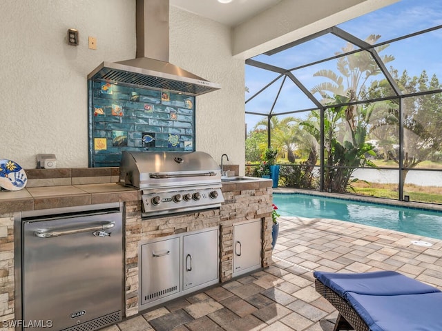 view of patio with area for grilling, an outdoor kitchen, a lanai, and sink