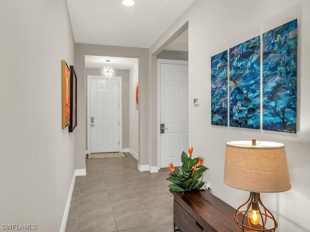 hallway with light tile floors and an inviting chandelier