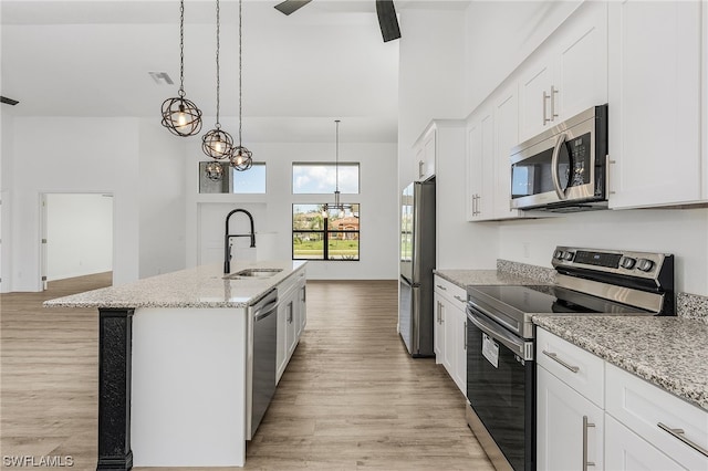 kitchen featuring a kitchen island with sink, hanging light fixtures, white cabinets, light hardwood / wood-style floors, and stainless steel appliances