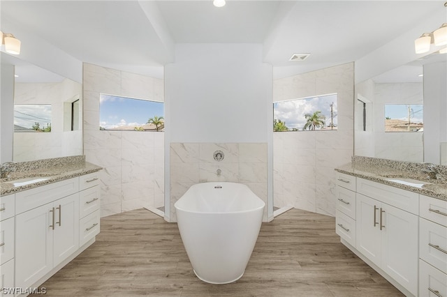 bathroom featuring a bathing tub, hardwood / wood-style flooring, and tile walls