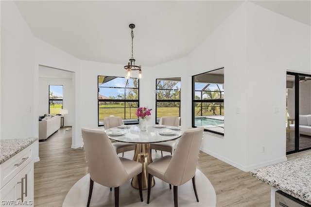 dining space with a notable chandelier, lofted ceiling, and light hardwood / wood-style flooring