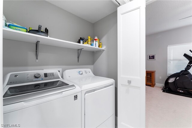 clothes washing area with washer and dryer and light colored carpet