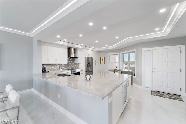 kitchen with light stone counters, a raised ceiling, stainless steel appliances, tasteful backsplash, and white cabinetry