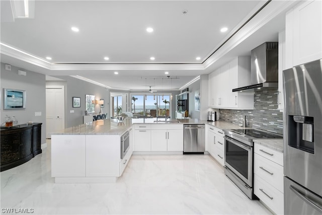 kitchen featuring white cabinets, appliances with stainless steel finishes, and wall chimney range hood