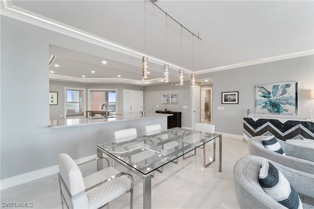 dining space with track lighting, a tray ceiling, sink, and ornamental molding