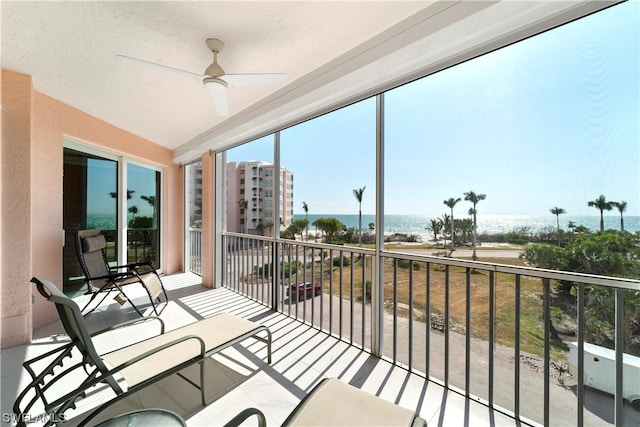 sunroom with a water view and ceiling fan