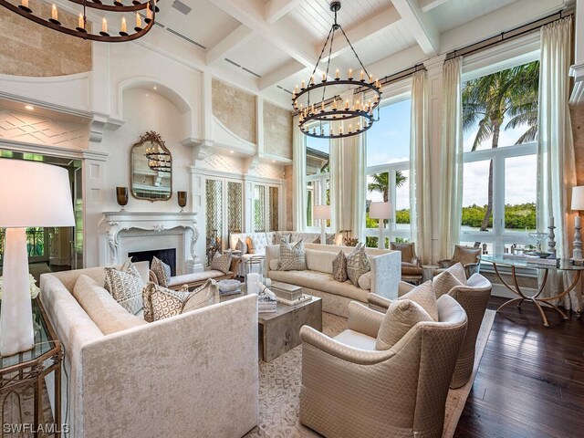 living room featuring a chandelier, beamed ceiling, coffered ceiling, wood-type flooring, and a high end fireplace