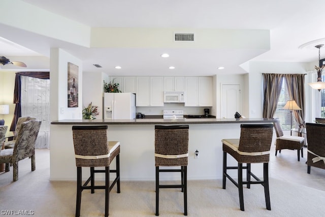 kitchen with pendant lighting, white appliances, white cabinets, and a breakfast bar