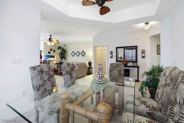 living room with a raised ceiling and ceiling fan