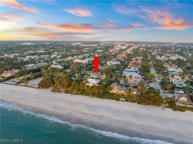 aerial view at dusk with a water view and a view of the beach