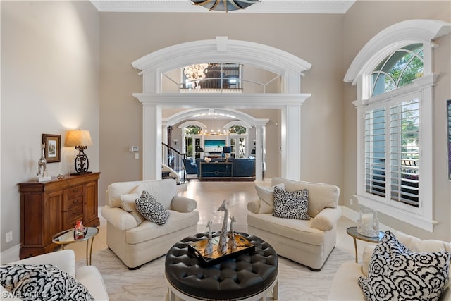 living room with ornamental molding, a high ceiling, and an inviting chandelier