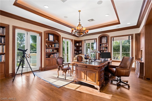 office area with a raised ceiling, a wealth of natural light, wood-type flooring, and an inviting chandelier