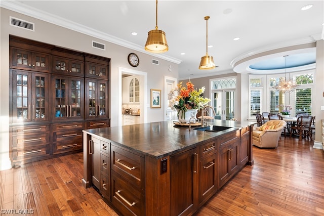 kitchen featuring an island with sink, hardwood / wood-style flooring, crown molding, and sink