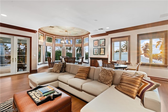 living room with french doors, ornamental molding, a notable chandelier, and hardwood / wood-style flooring