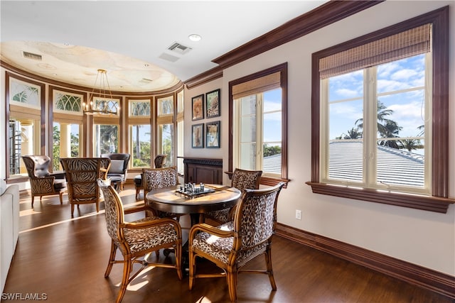 dining room with dark wood-type flooring, a chandelier, and ornamental molding