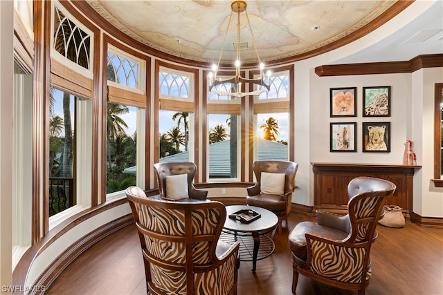 sitting room featuring hardwood / wood-style floors, ornamental molding, and a notable chandelier