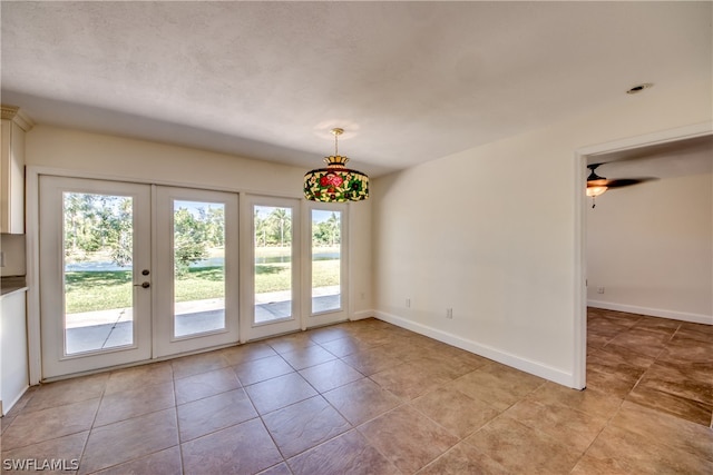 tiled empty room featuring french doors and ceiling fan