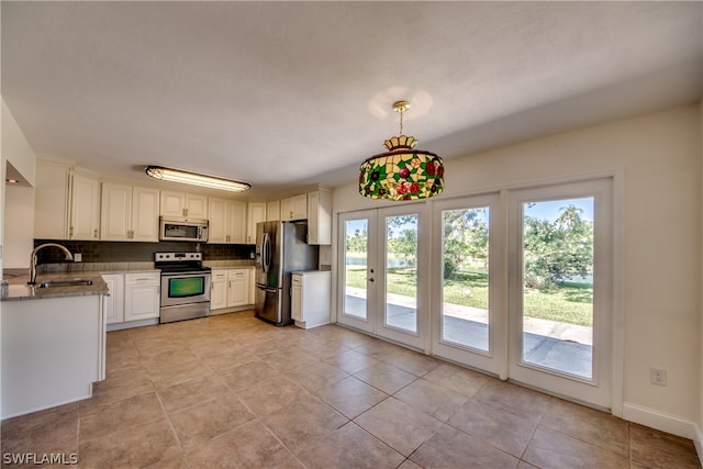 kitchen featuring stainless steel appliances, light tile floors, sink, and hanging light fixtures