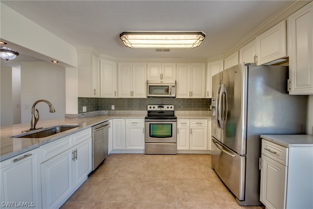 kitchen with appliances with stainless steel finishes, light tile floors, white cabinets, sink, and backsplash