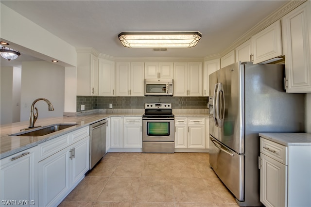 kitchen with white cabinets, light tile flooring, stainless steel appliances, sink, and tasteful backsplash