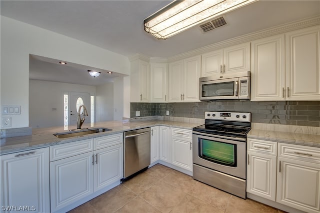 kitchen with sink, appliances with stainless steel finishes, white cabinetry, and light tile floors