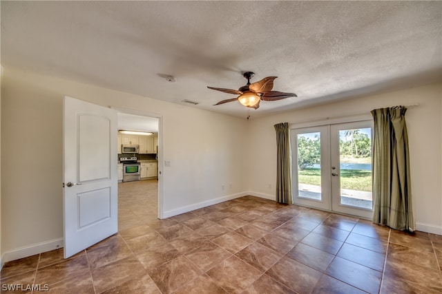 tiled empty room with french doors, ceiling fan, and a textured ceiling