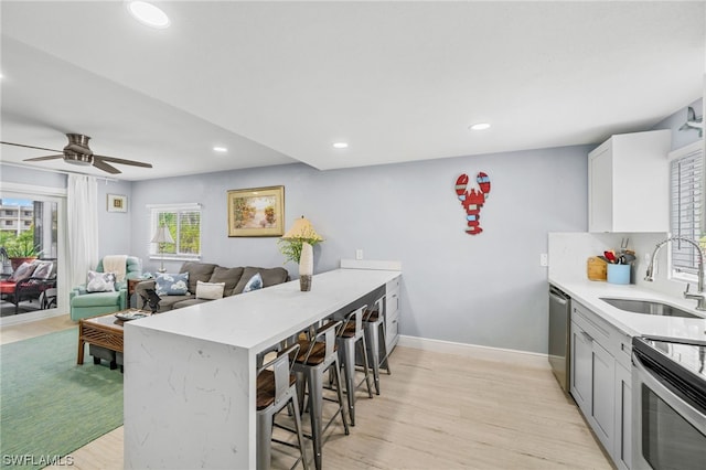 kitchen featuring kitchen peninsula, white cabinetry, ceiling fan, light hardwood / wood-style floors, and sink