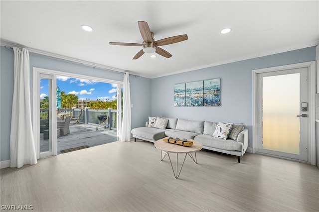 living room with crown molding, light hardwood / wood-style floors, and ceiling fan