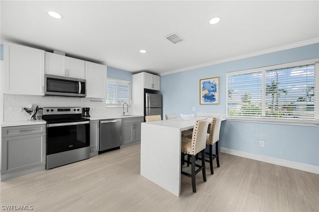 kitchen with a breakfast bar area, tasteful backsplash, appliances with stainless steel finishes, and a wealth of natural light