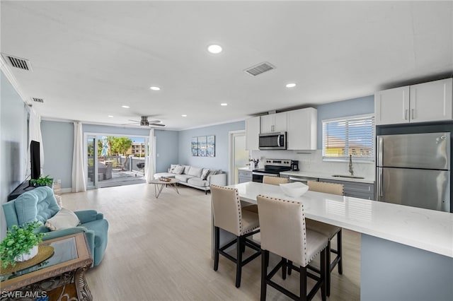 kitchen featuring white cabinetry, ceiling fan, appliances with stainless steel finishes, and light wood-type flooring