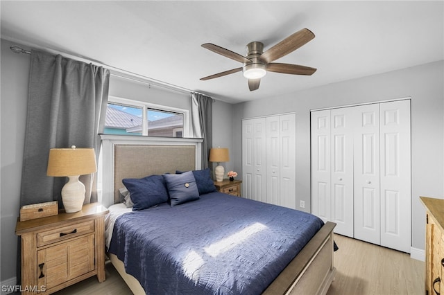 bedroom featuring light hardwood / wood-style floors, ceiling fan, and two closets