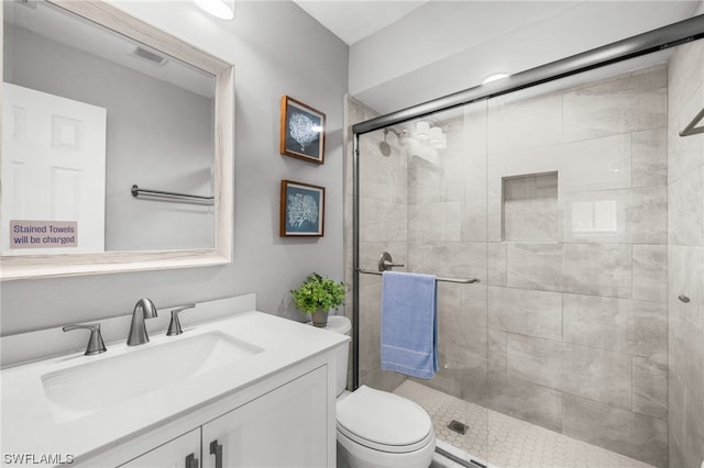 bathroom with toilet, an enclosed shower, and vanity