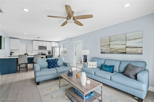 living room with ceiling fan and light hardwood / wood-style flooring