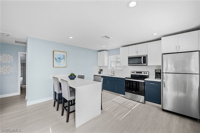 kitchen featuring light hardwood / wood-style floors, blue cabinets, stainless steel appliances, and a breakfast bar area